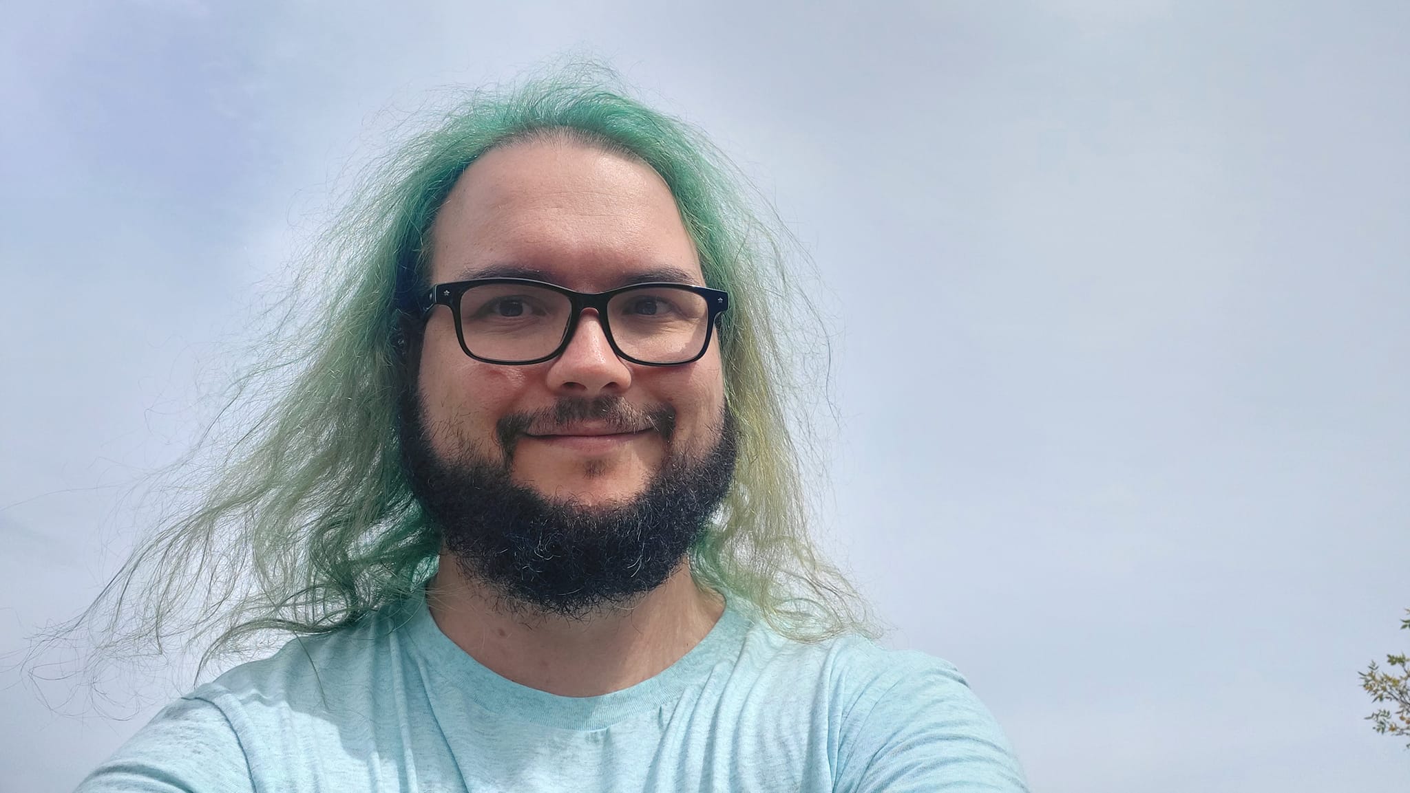 A man with green hair stands with only the sky visible in the background, Photo 2